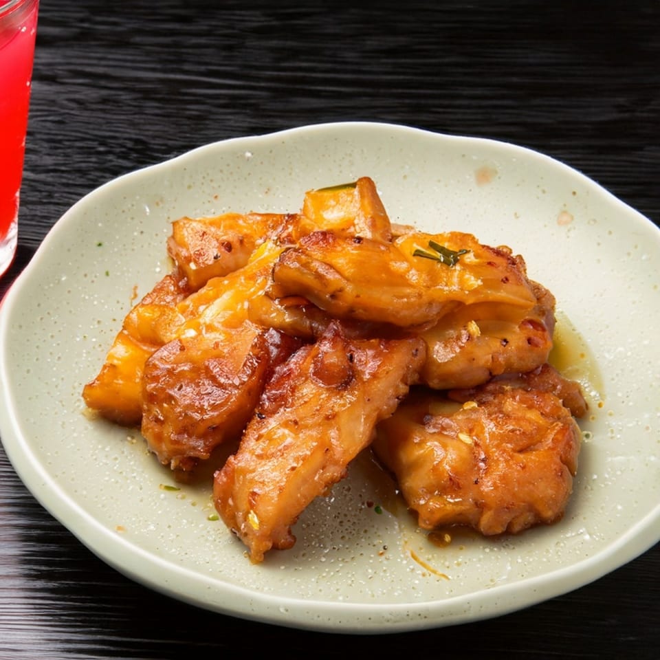 Golden-brown boneless wings, glazed with sauce and garnished with herbs, on a light plate.