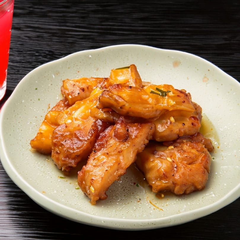 Golden-brown boneless wings, glazed with sauce and garnished with herbs, on a light plate.